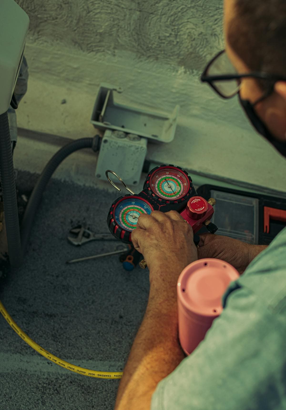 The AC Boys technician using refrigerant manifold gauges to diagnose an AC repair