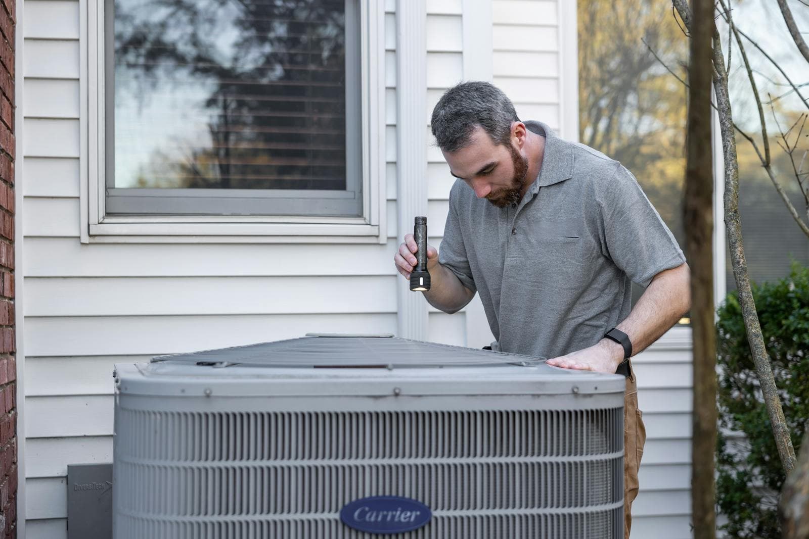 The AC Boys technician inspecting a residential air conditioning unit in Broward County